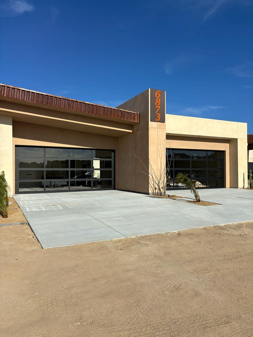 Modern commercial building exterior with large glass doors and clear blue sky.