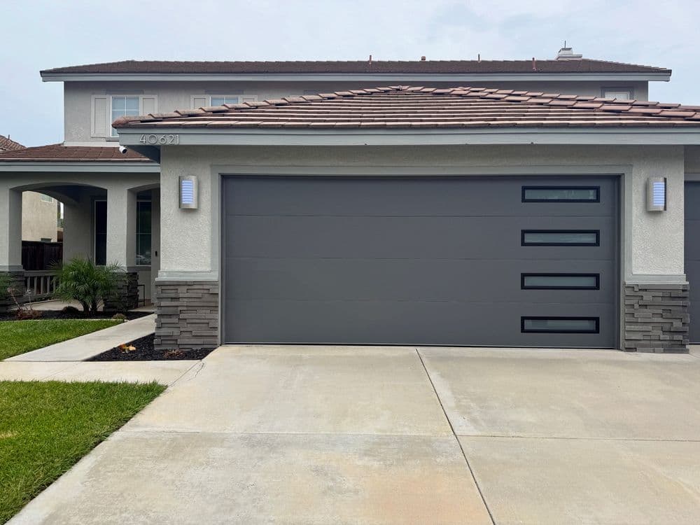 Modern gray garage door with horizontal panels on a contemporary home exterior.